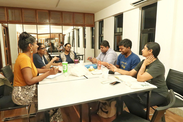 Six persons seated around a table in the 42 Waterloo Street Meeting Room, smiling and talking to one another.