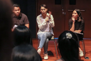 Nessa Anwar flanked by two persons, seated in the 42 Waterloo Street Black Box speaking to an audience.