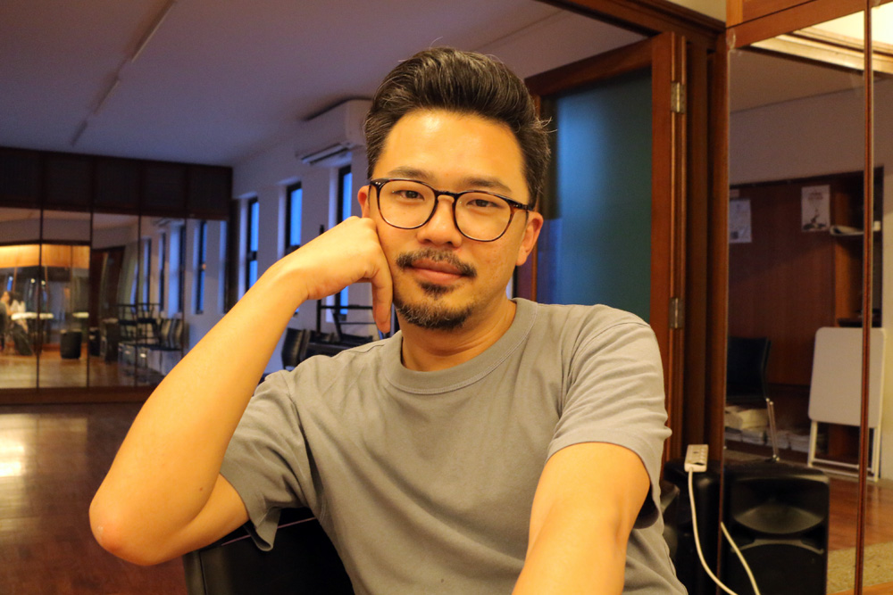 Rei Poh seated in the 42 Waterloo Street Meeting Room with his face resting against his right fist.