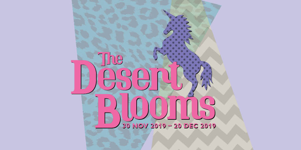 A horizontal purple rectangle with two overlapping triangles in the centre; the triangle on top has a blue leopard print pattern and the one at the bottom has a brown and yellow zigzag pattern. Overlayed on the triangles is a purple unicorn on its hind legs. To its left are the words 'The Desert Blooms' in pink font.