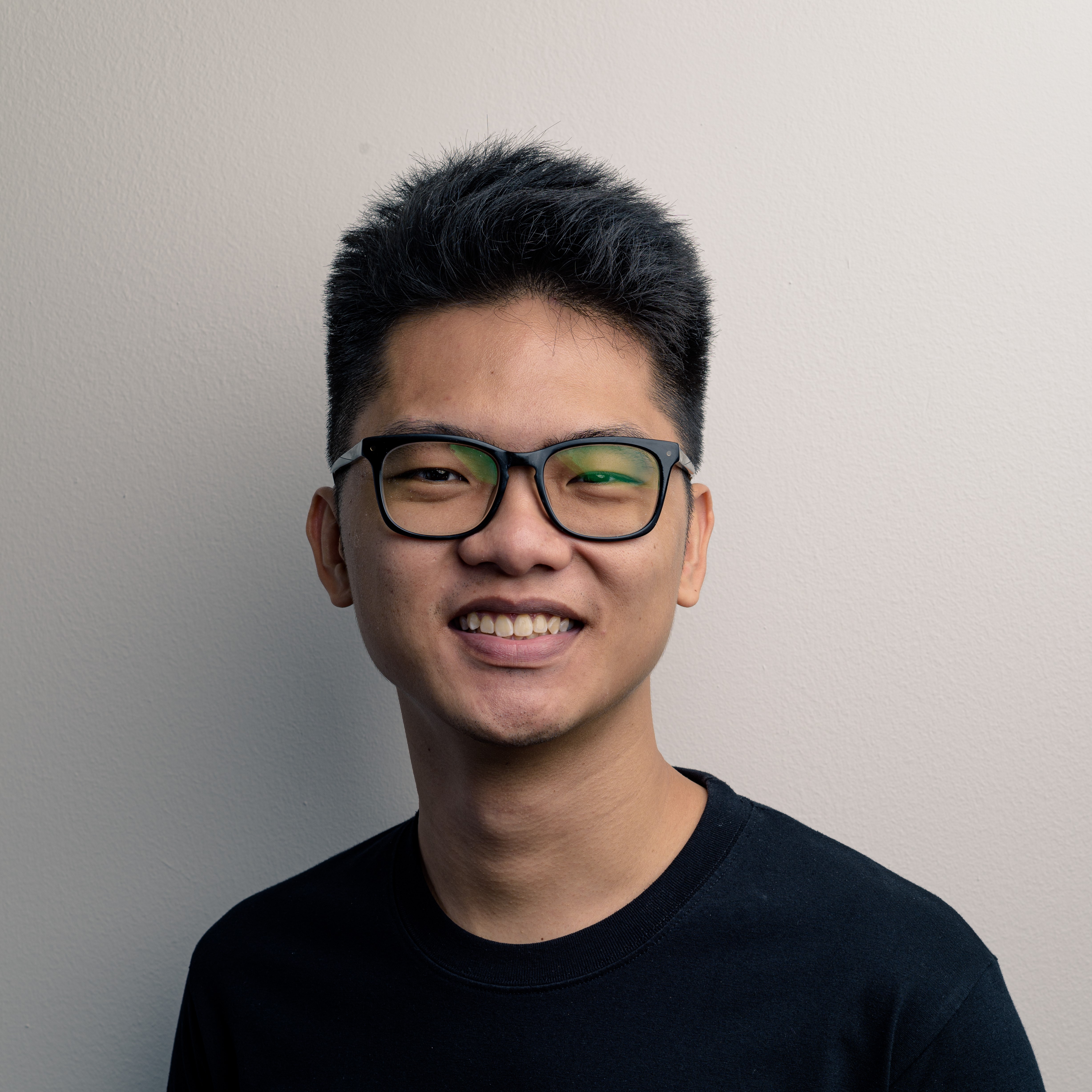 The photograph features a bespectacled man smiling wearing a black shirt.