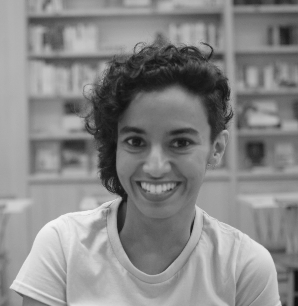 Black and white headshot of Akanksha Raja with shelves in the background.