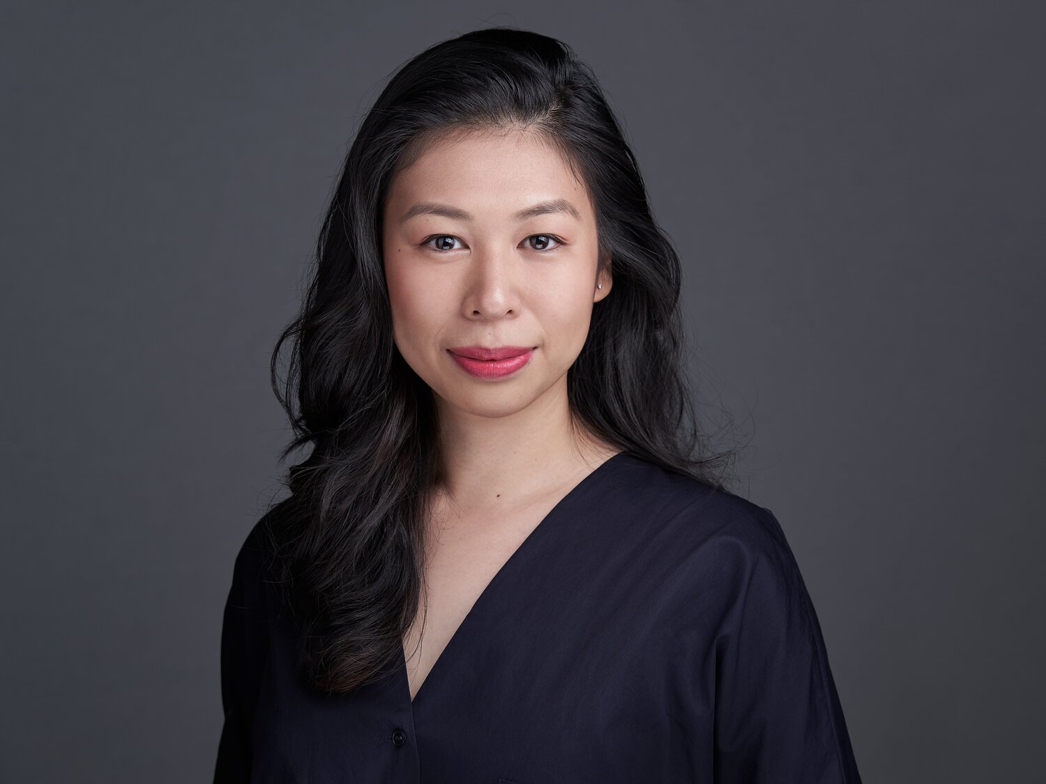 Coloured headshot of Cherilyn Woo, against a grey background and wearing a dark coloured.