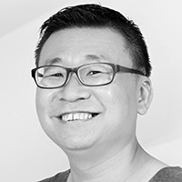 A black and white headshot of Kok Heng Leun, in glasses, smiling into the camera.