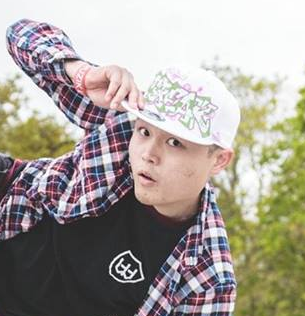 A headshot of Dominic Nah in a white cap and plaid jacket, looking into the camera.