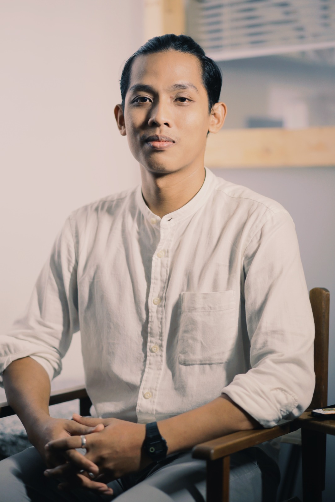 An image of Hairi Cromo seated and wearing a white button up top. 