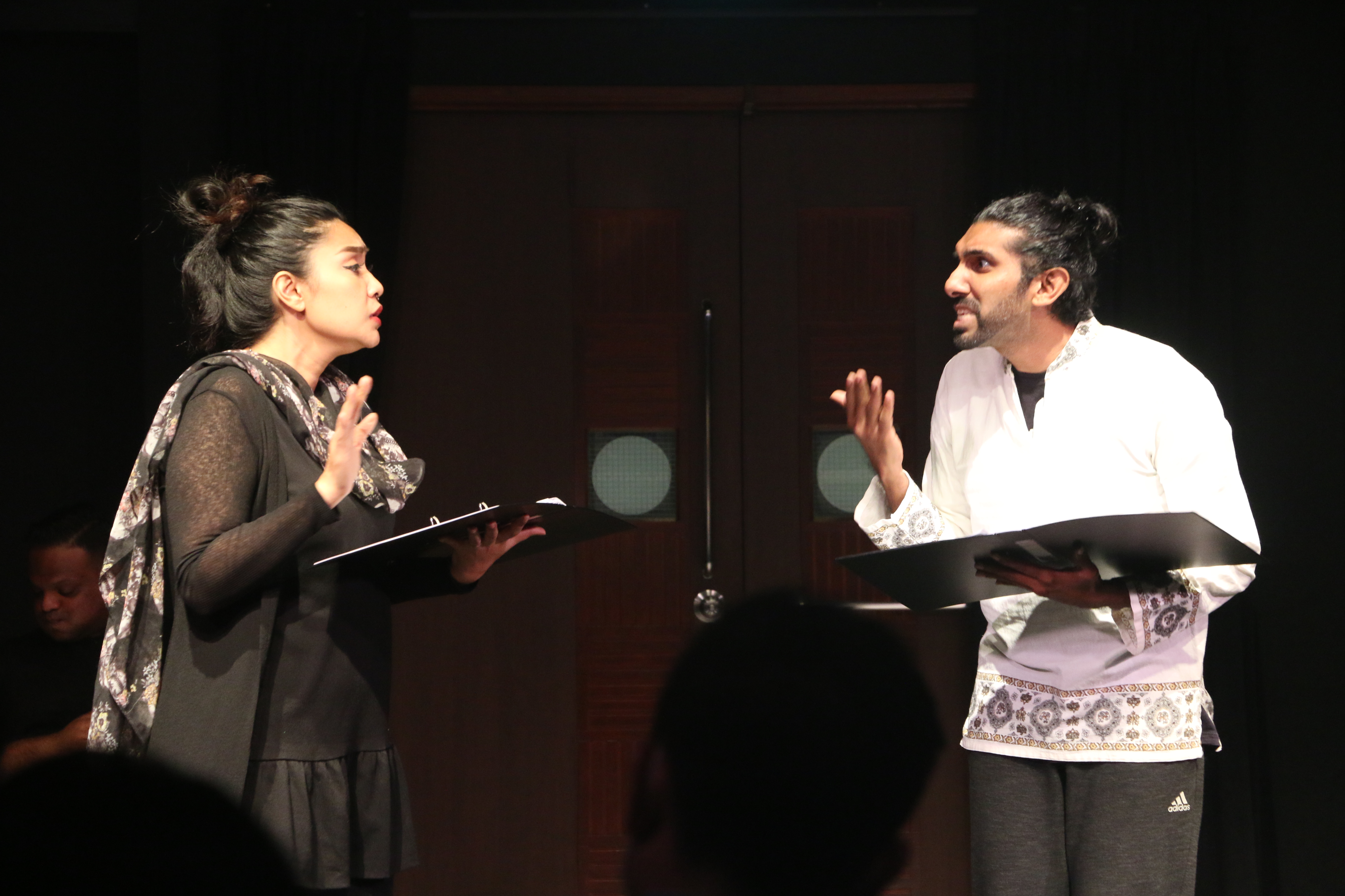 The photograph features a man dressed in white arguing with a woman dressed in black.