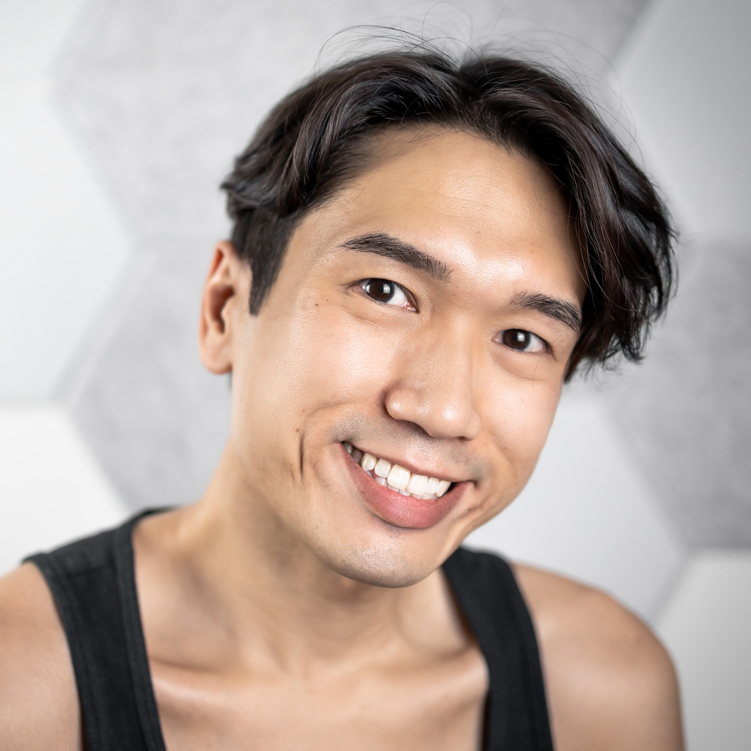 An image of Daniel Teo, dressed in a sleeveless black top with short wavy hair.