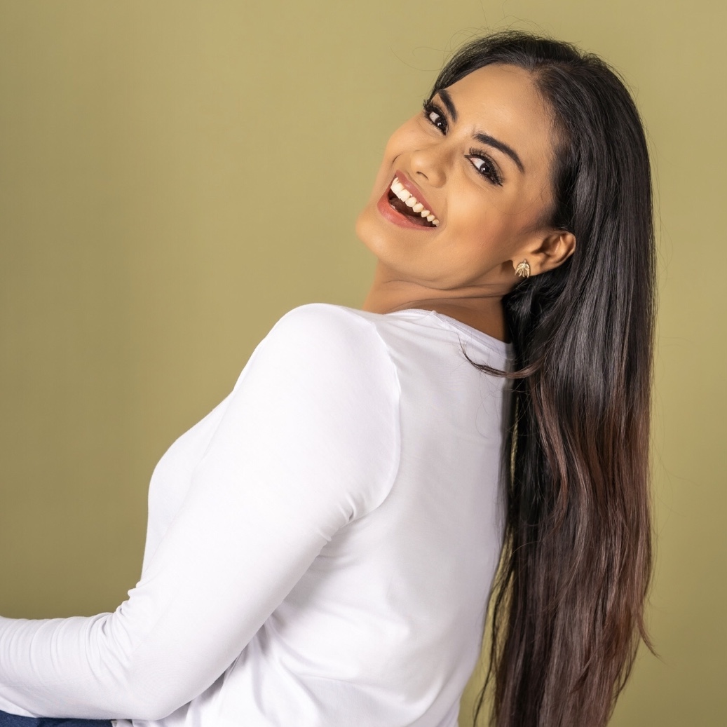 An image of Rebekah Sangeetha Dorai smiling widely in a long sleeve white top.