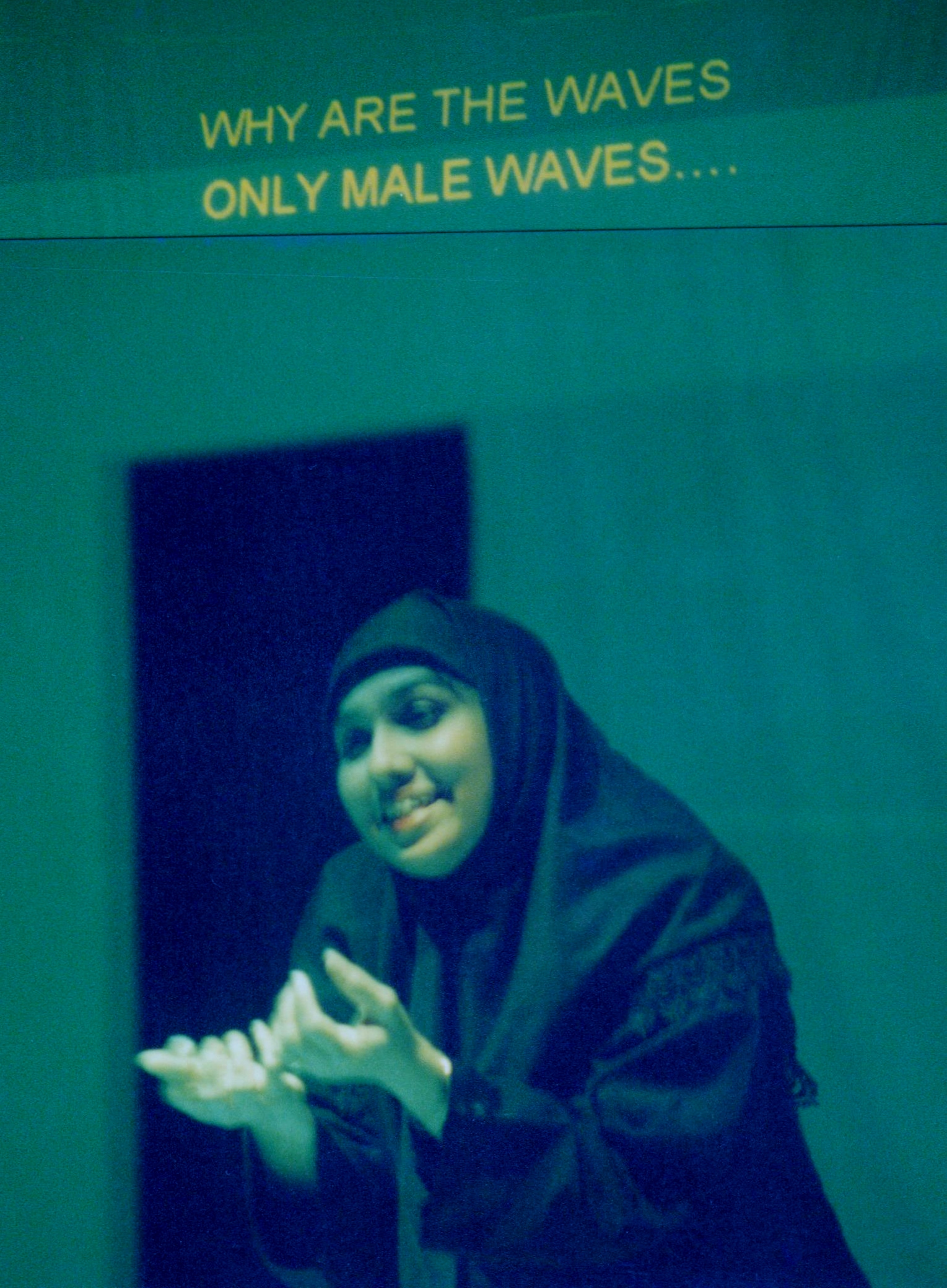 The image features a woman in a headscarf holding up her hands in the action of pleading. There is text printed above her, which reads "Why are the waves only male waves..."