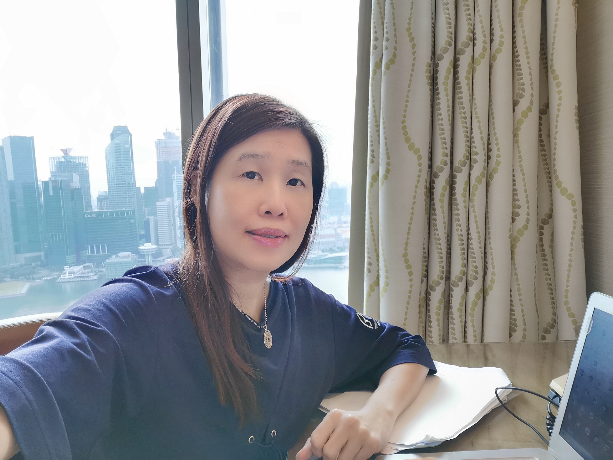 Beverly Yuen at a desk in a hotel room.