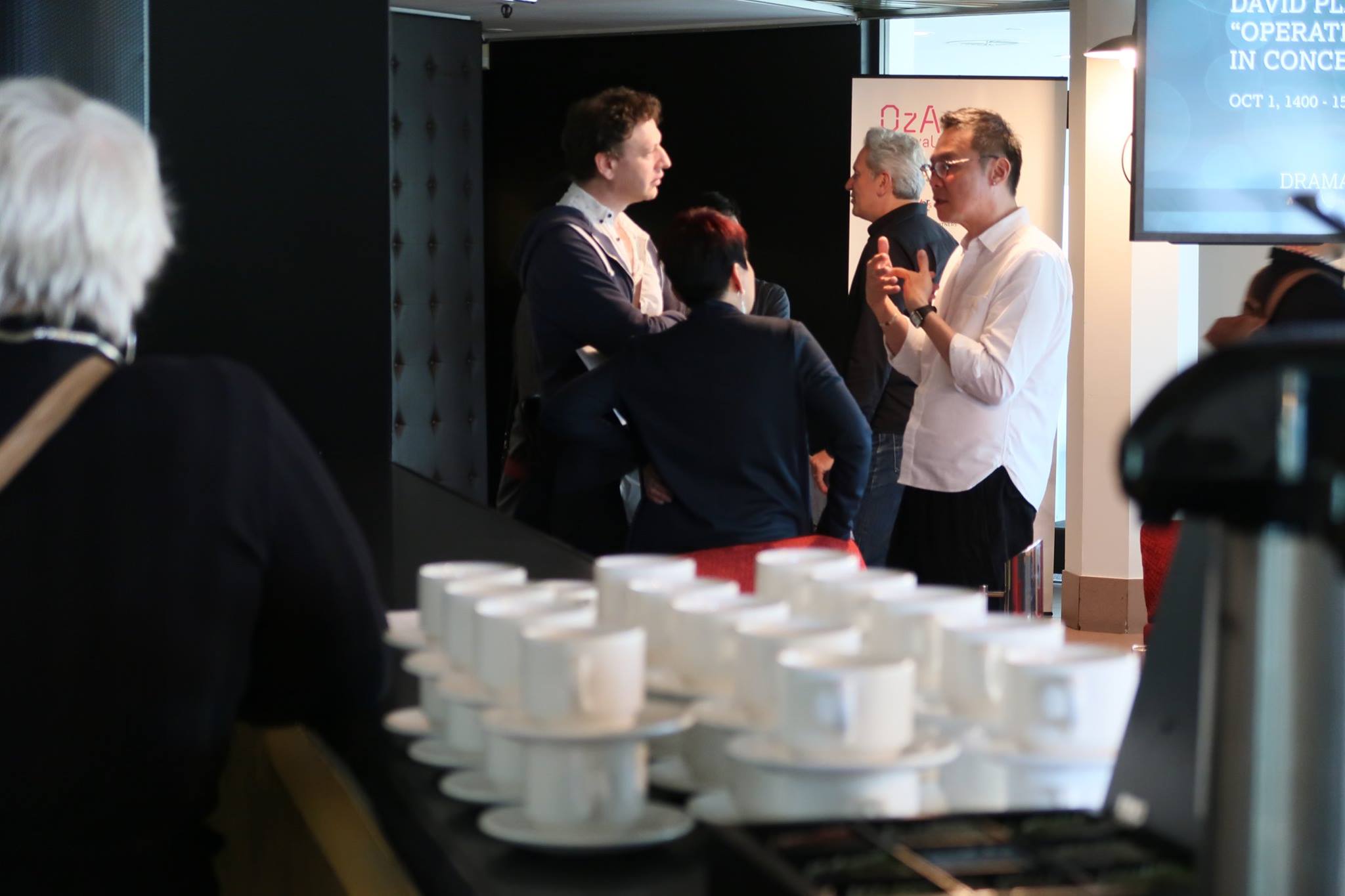 Four persons conversing in a corner in front of several coffee cups.