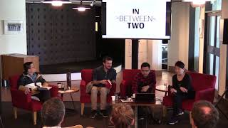 Four persons seated in red chairs under a raised TV screen.