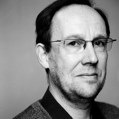 Black and white headshot of Guy Cools in glasses.