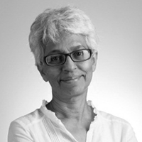 Black and white headshot of Janet Pillai, wearing glasses and smiling.