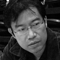 Black and white headshot of Ken Takiguchi in glasses.