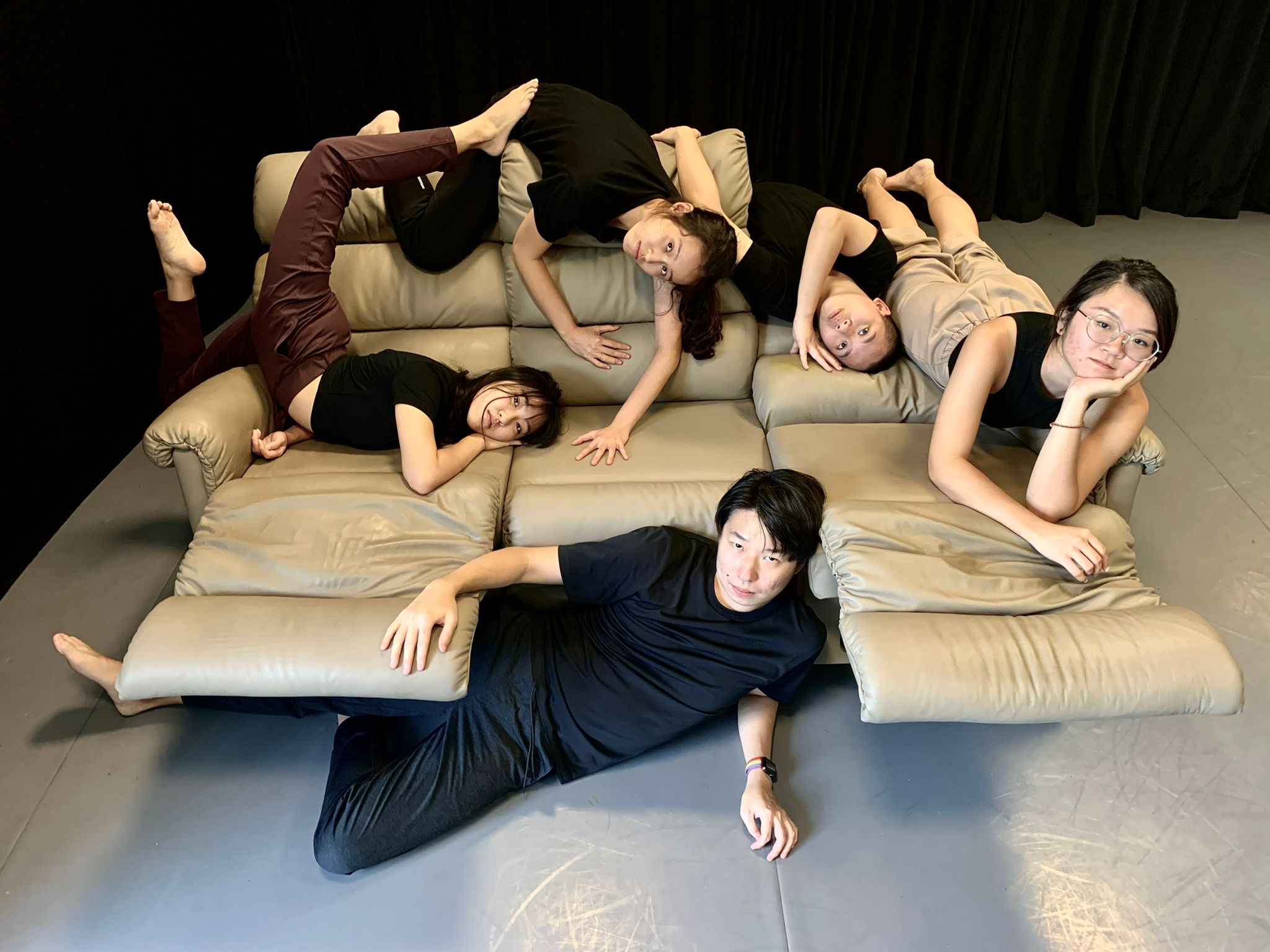 An image of five members of ZOBO Company sprawled out across a beige leather sofa. 