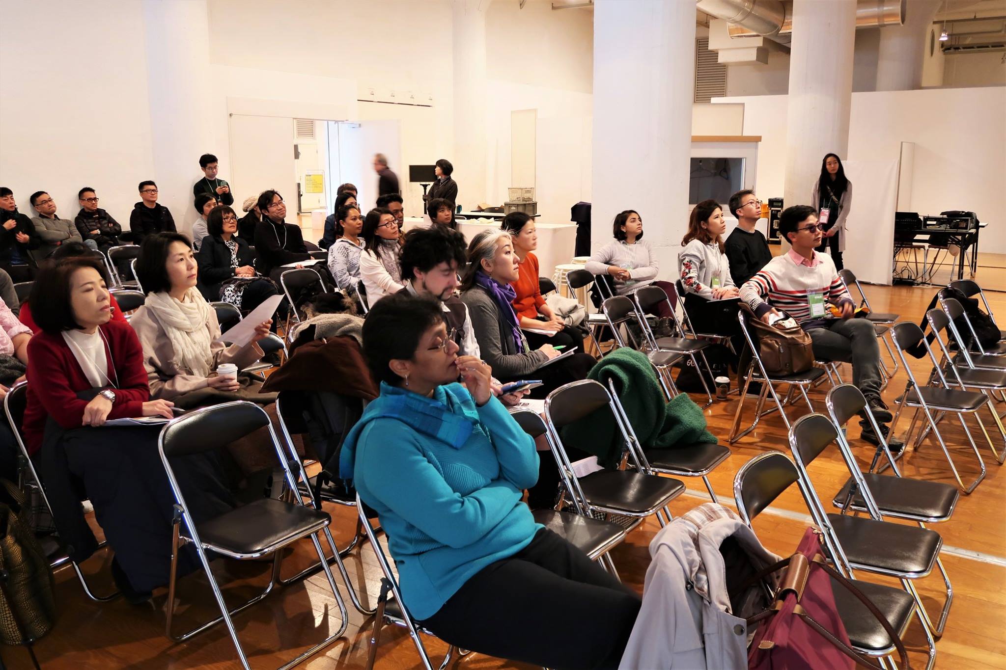 Several rows of audience members seated in folding chairs.