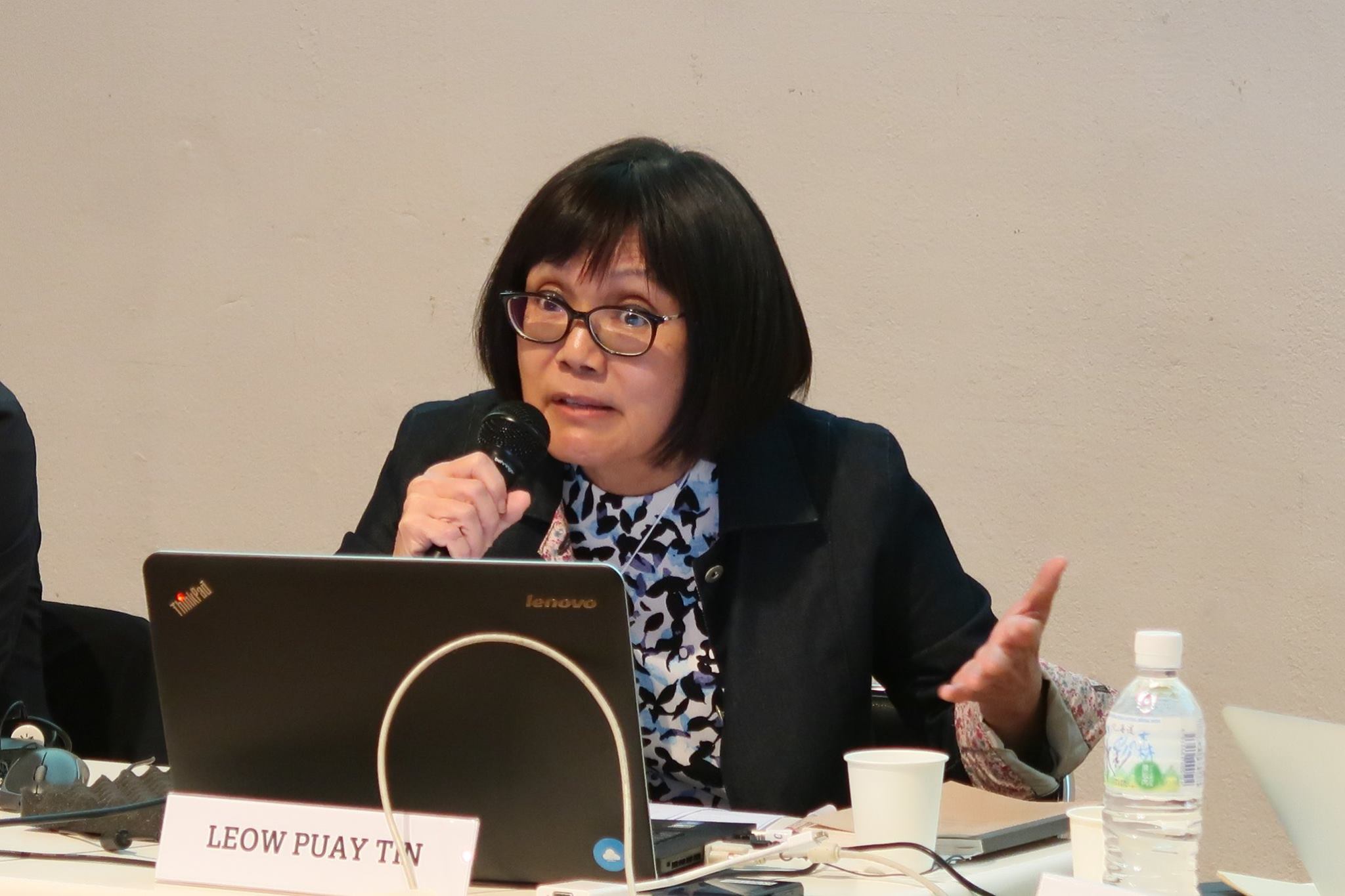 A female-presenting person, wearing glasses, speaking into a microphone.