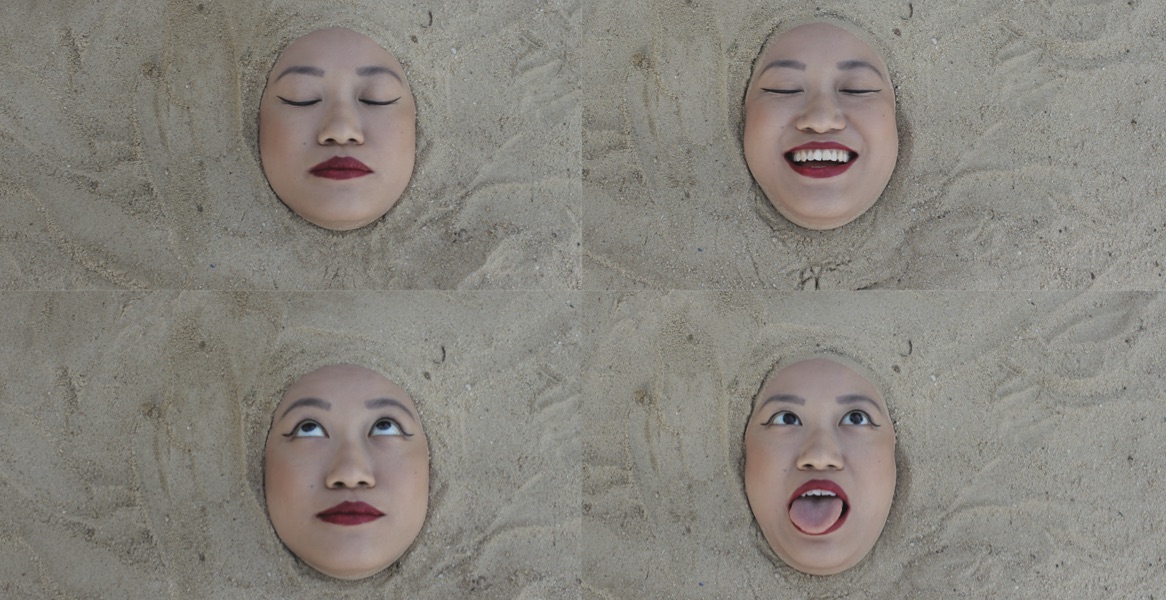 Four faces with differing expressions, buried in the sand.