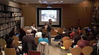 A large audience sitting facing a projector screen.