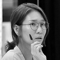 Black and white headshot of Jae Lee Kim holding a pen and wearing glasses.