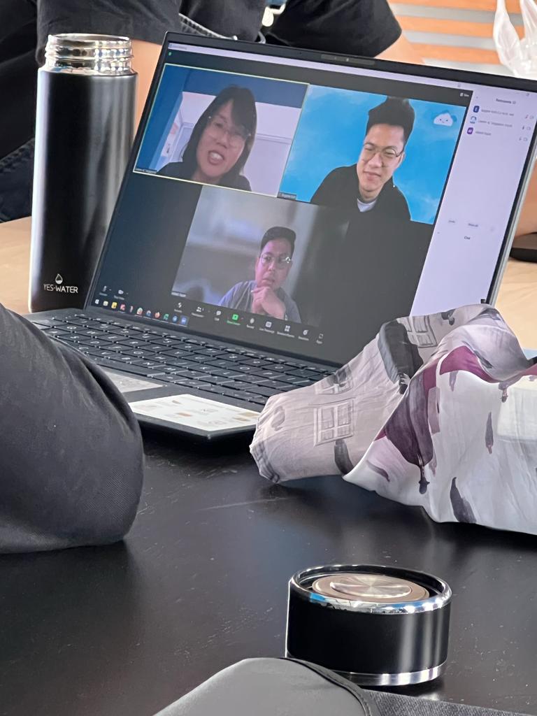 A laptop on a table with the ZOOM app open. Three persons are having a ZOOM meeting.