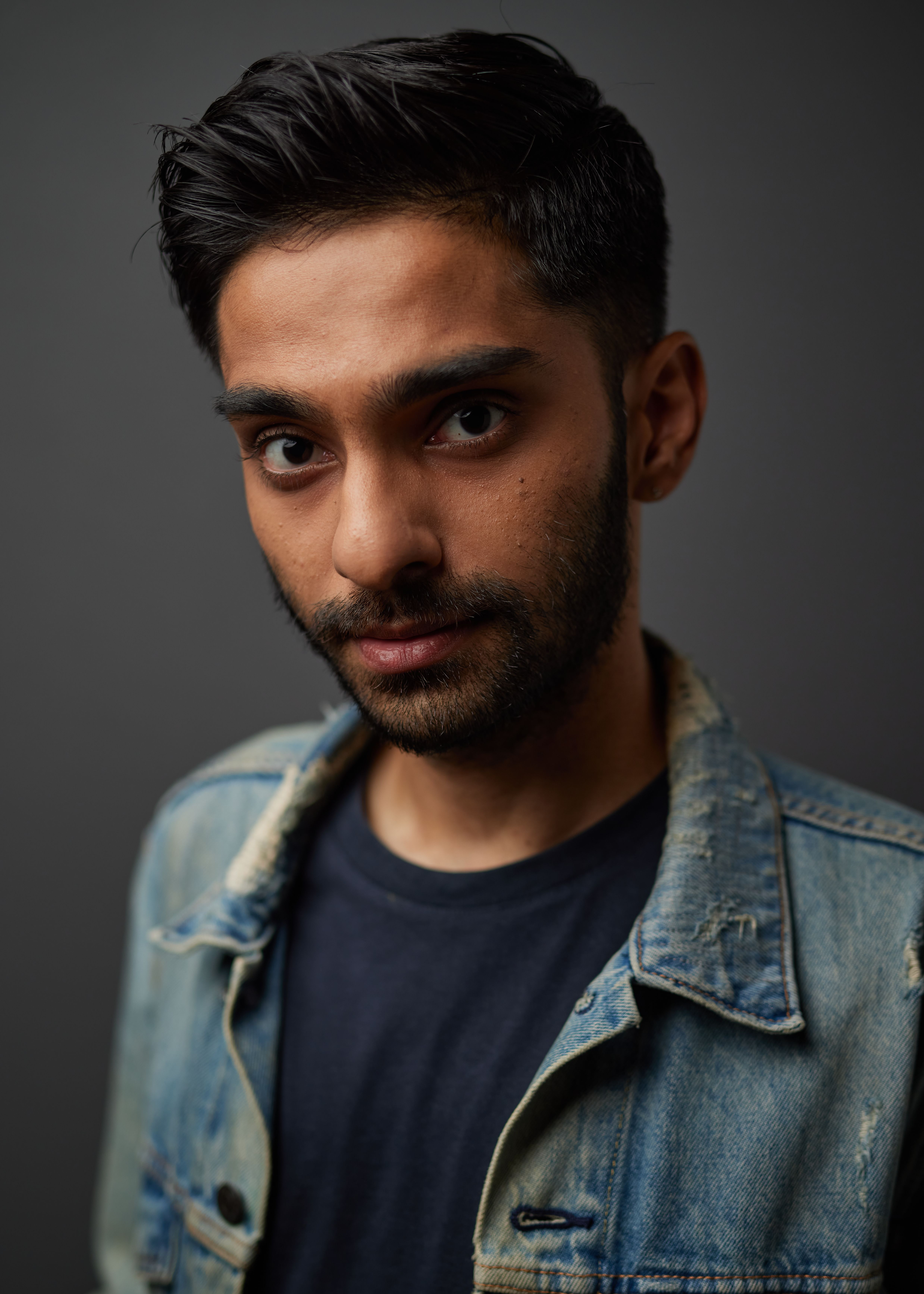 Headshot of Vignesh Singh in a blue shirt and denim jacket, glancing into the camera.