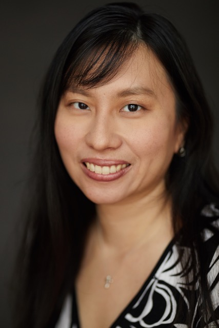 Headshot of Jean Tay wearing a necklace, with long hair, smiling.