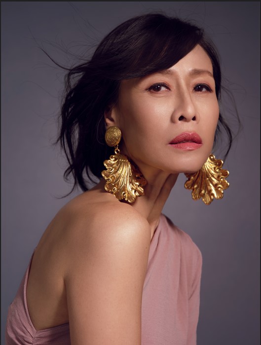 Upper-body shot of Tan Kheng Hua in a pink top, wearing golden earrings, staring into the camera.