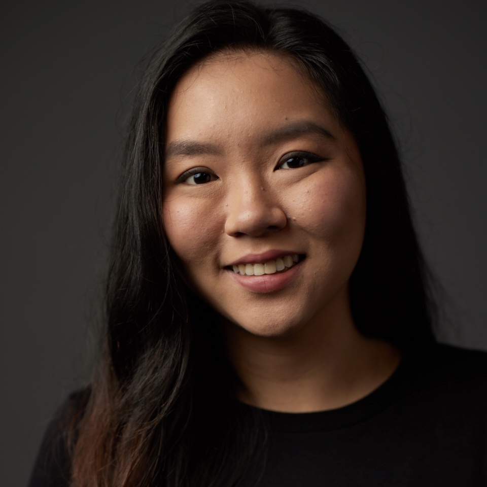 Headshot of Genevieve Tan in a black shirt, with long hair, smiling.