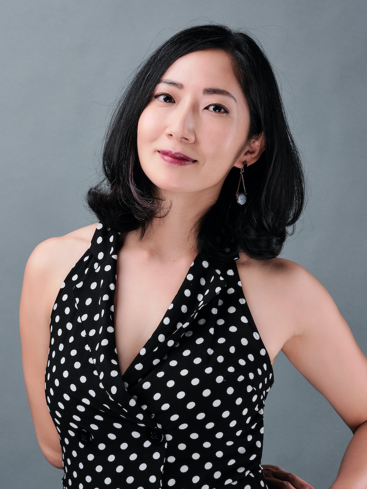 A half-body shot of Jo Tan, wearing a black and white polka dot sleeveless top.