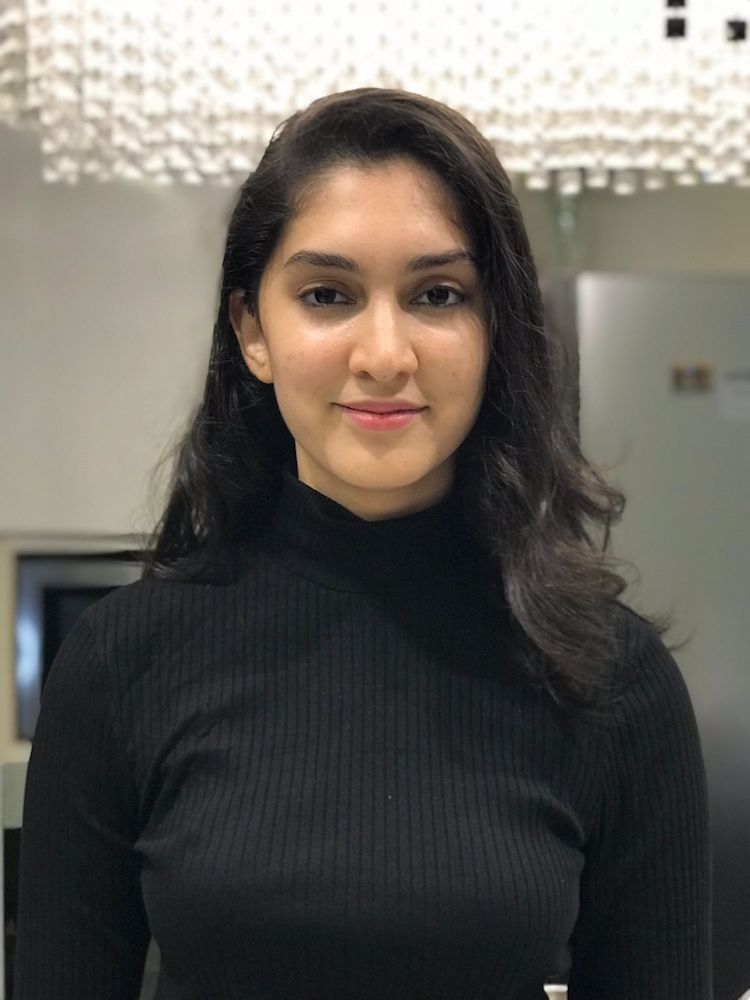 Headshot of Karthika Warrier in a long-sleeved black turtleneck, smiling slightly.