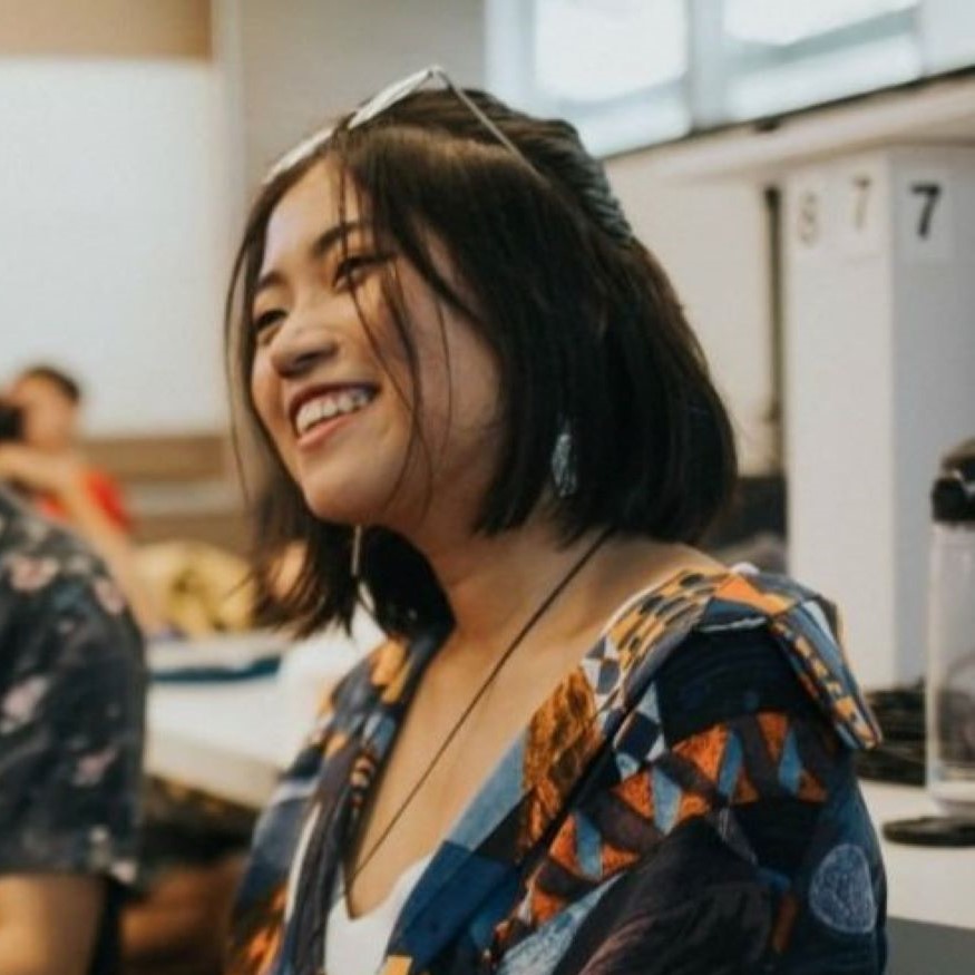 Candid headshot of Yeo Dana, wearing a colourful shirt and glasses atop her head, smiling.