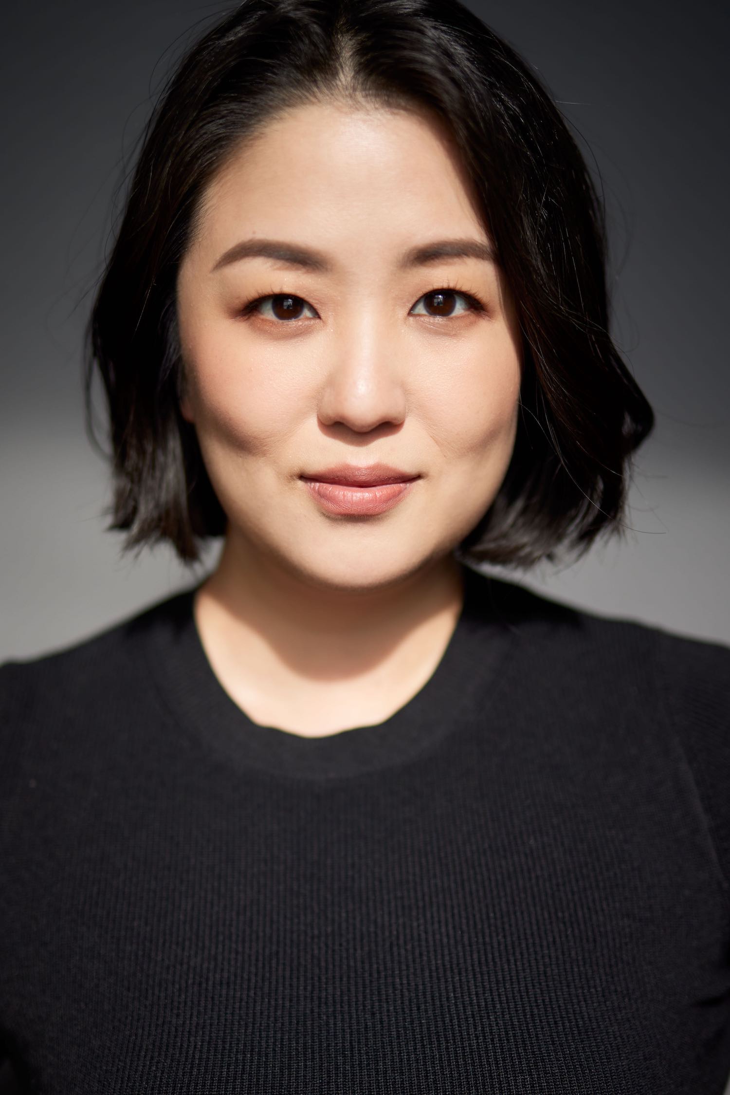 Headshot of Zee Wong in a black shirt, with short hair, smiling.