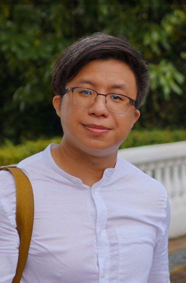 Half-body shot of Christopher Chee outdoors, wearing a white shirt and glasses, looking away from the camera.