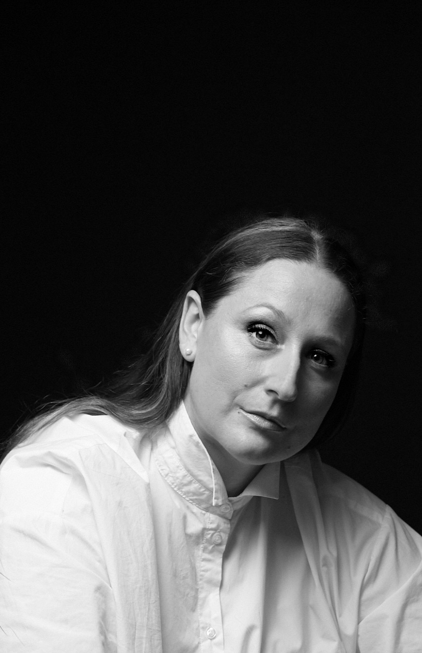 Black and white half-body shot of Edith Podesta in a white shirt, looking pensively at the camera.