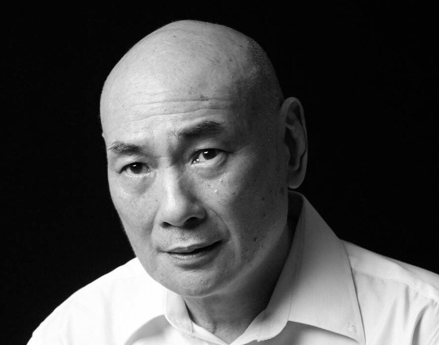 Black and white headshot of Lim Kay Siu looking pensive, wearing a white collared shirt.