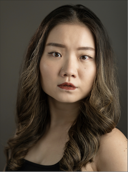 Headshot of Tiara Yap with curled, dyed golden-brown hair, staring neutrally into the camera.