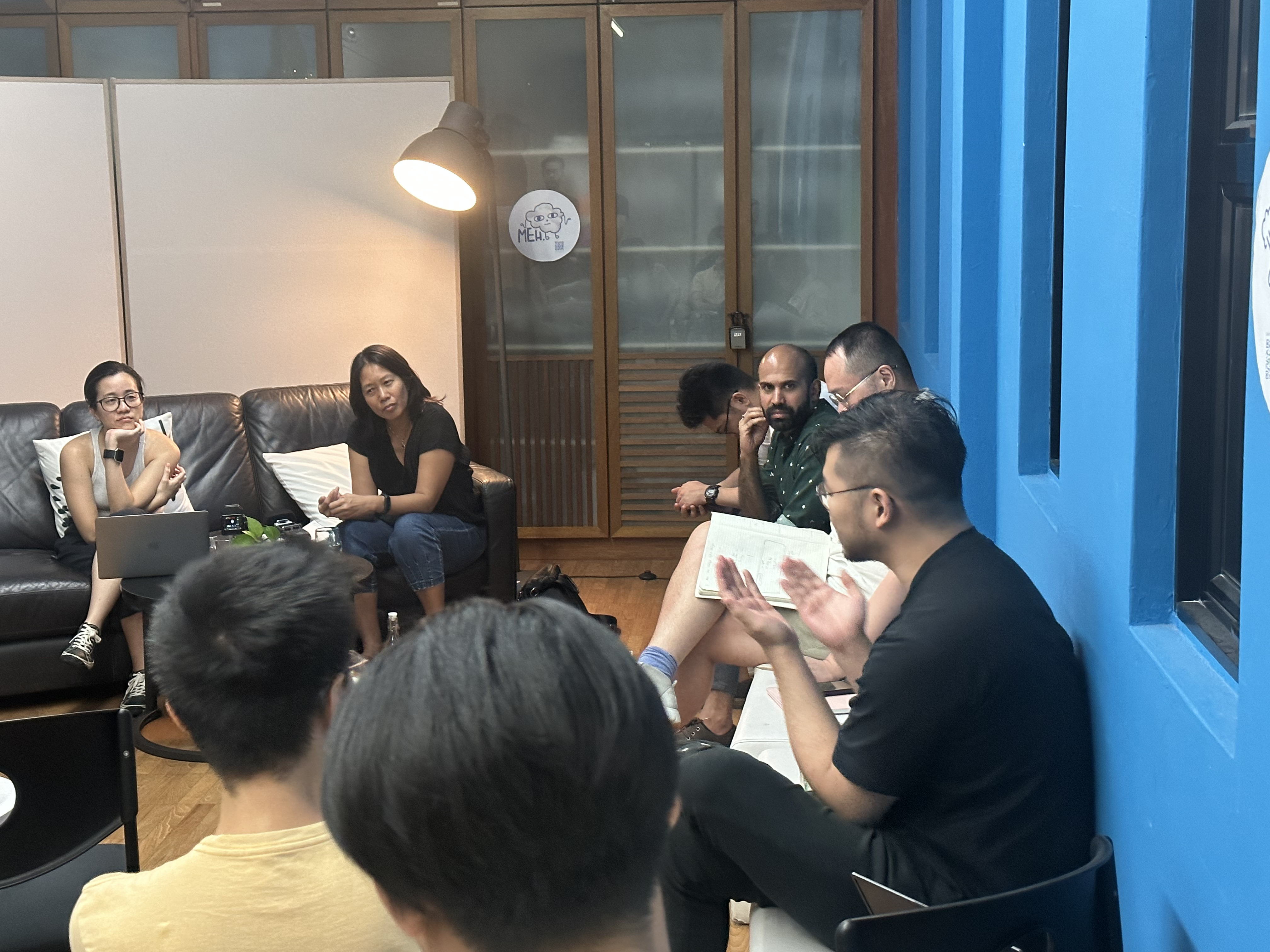 A photograph of Juliet and Michelle seated on a couch looking in the direction of an attendee with gesturing hands, asking a question.