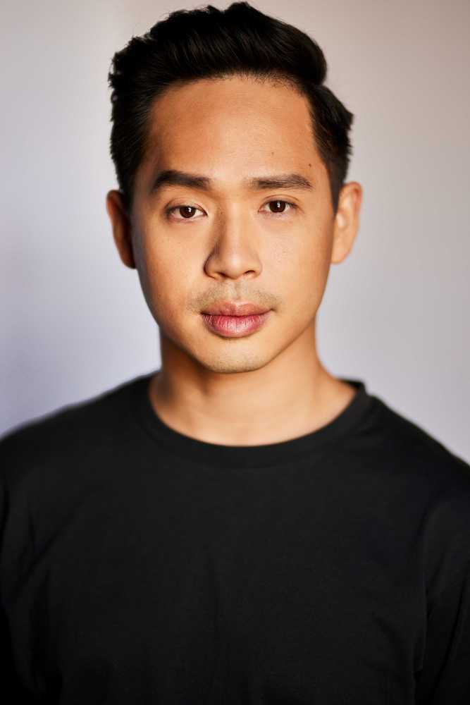 Headshot of Timothy Wan, with a neutral expression, wearing a black shirt.