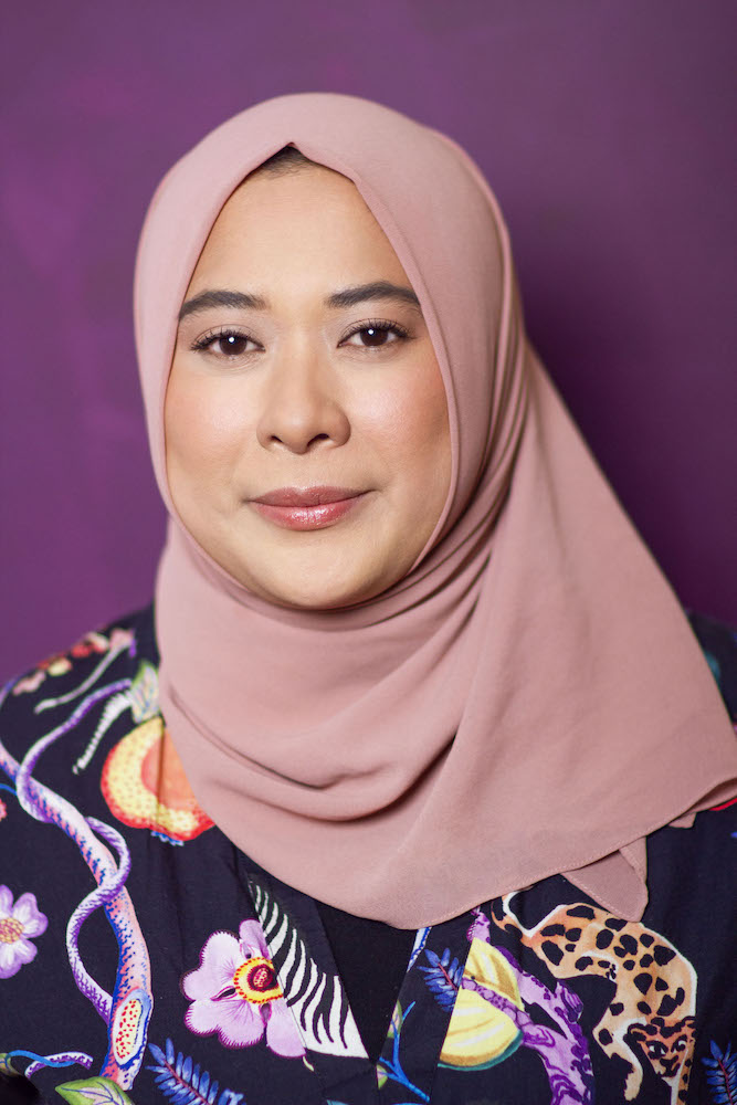 Headshot of Zizi Azah Abdul Majid, wearing a pink hijab and flower-patterned top.