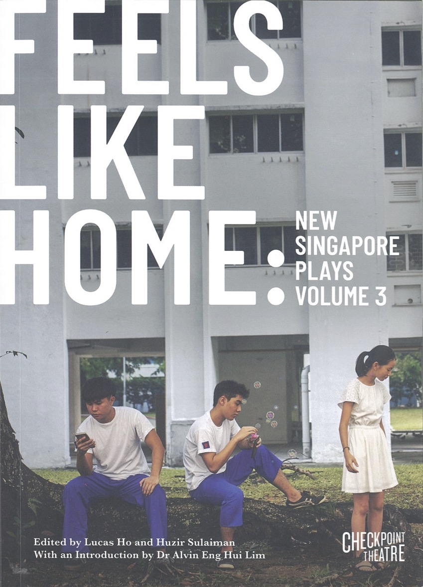 The publication features three persons in a grass field in front of a HDB building. Two are seated on a tree root and one stands in front of it, looking at the ground.