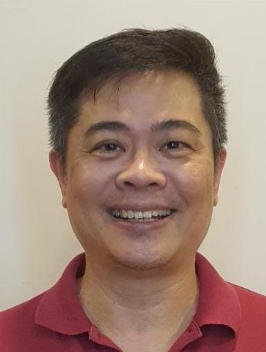 A male-presenting person in a red collared shirt, shot from the neck up.