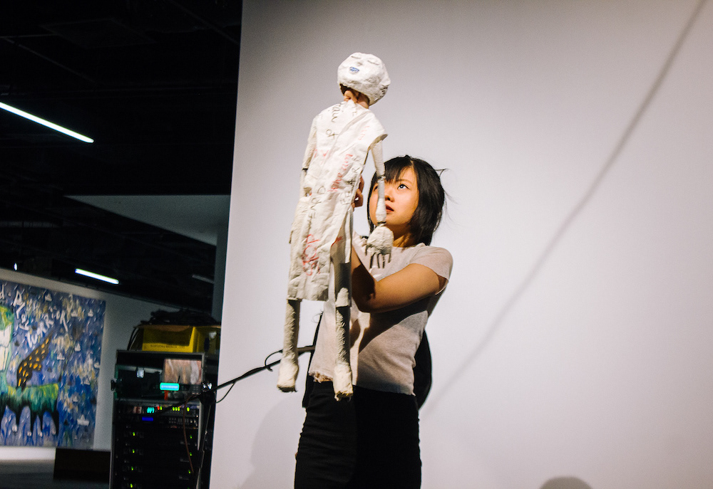 Female-presenting person holding a large white puppet in front of them.