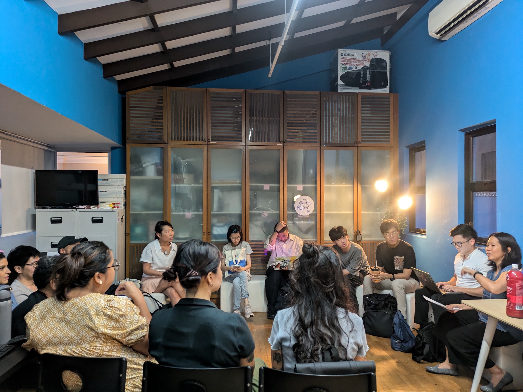 A group of people seated in a circle in a small office.