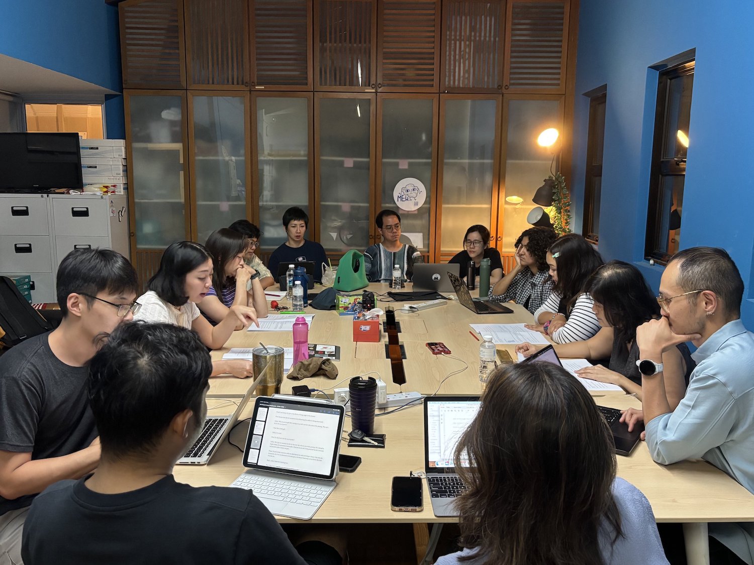 A large group of people seated around tables in an office.