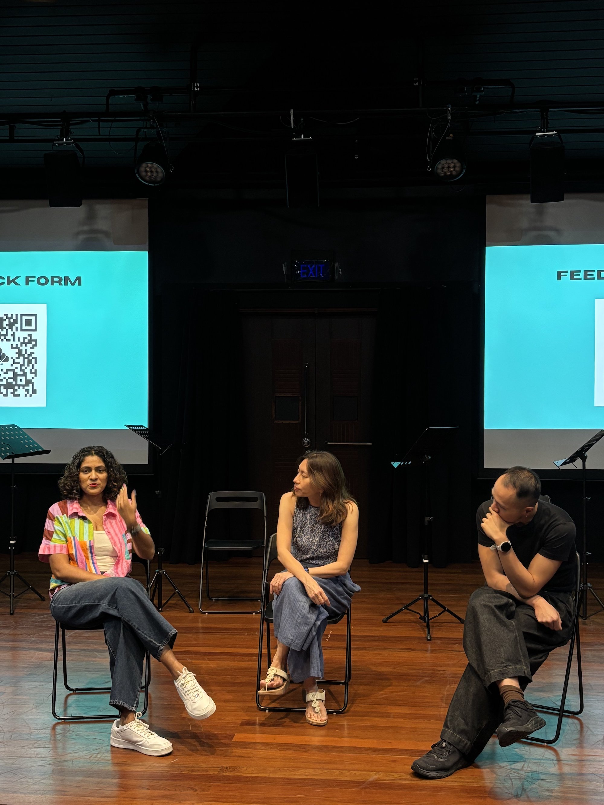 Three persons seated in chairs, talking.